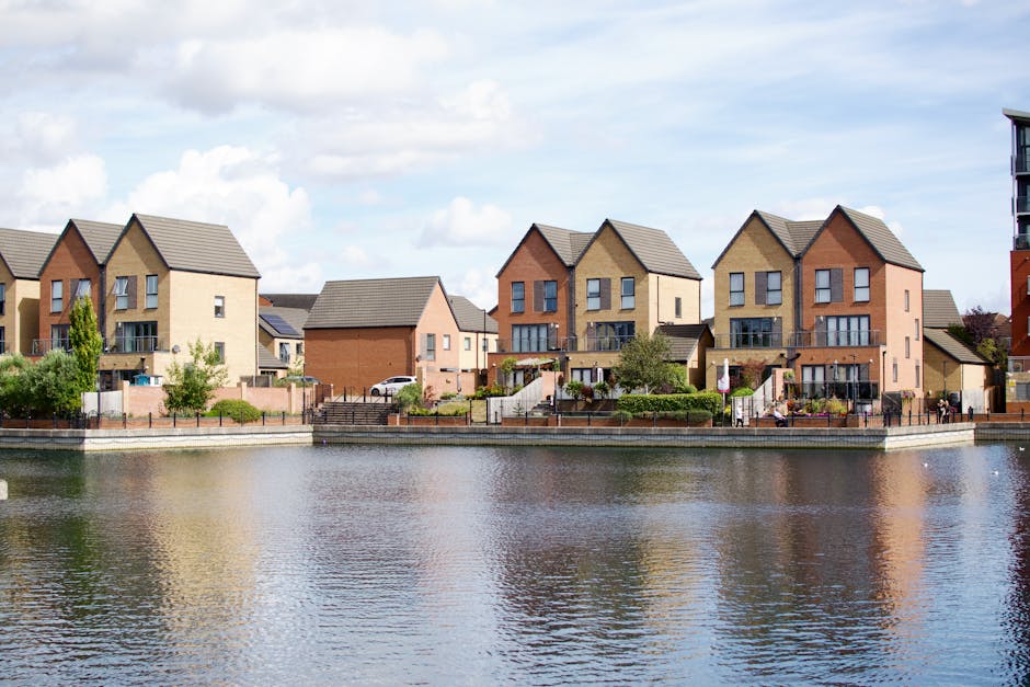 View along a canal with several narrowboats moored to the banks, featuring boats with dark-colored exteriors and covered covers, some with metallic railings and small outboard motors at the stern. On